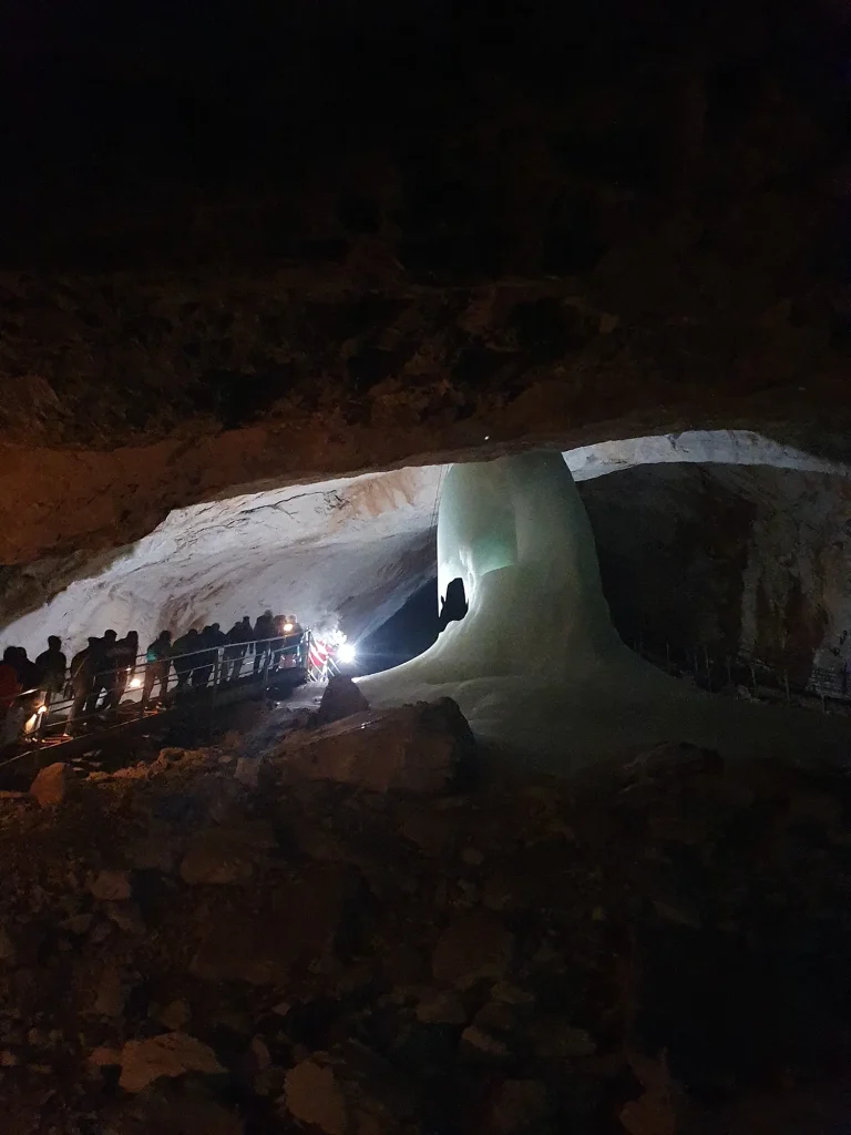 Ice cave with a line of people walking in the dark.