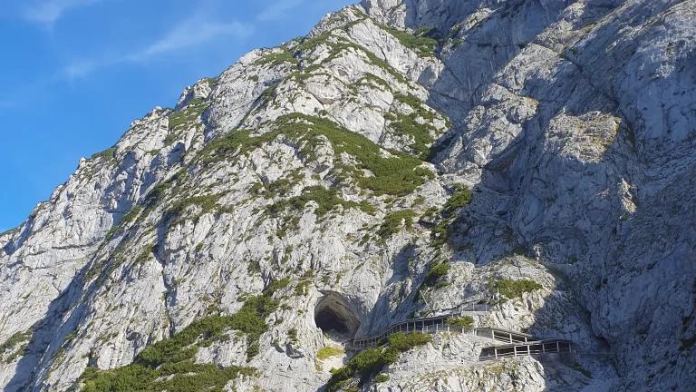 Rocky mountain with a path going into a ice cave in Austria.